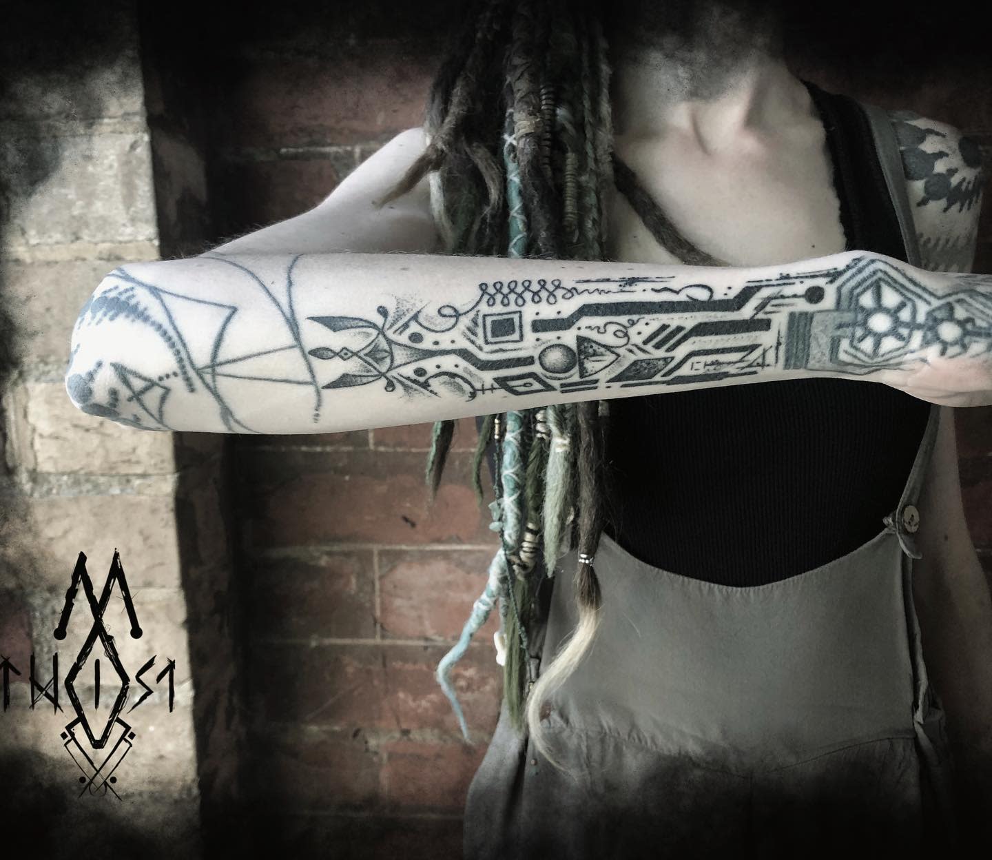 A forearm tattoo featuring a mix of cyberpunk circuitry and tribal designs, creating a unique futuristic look